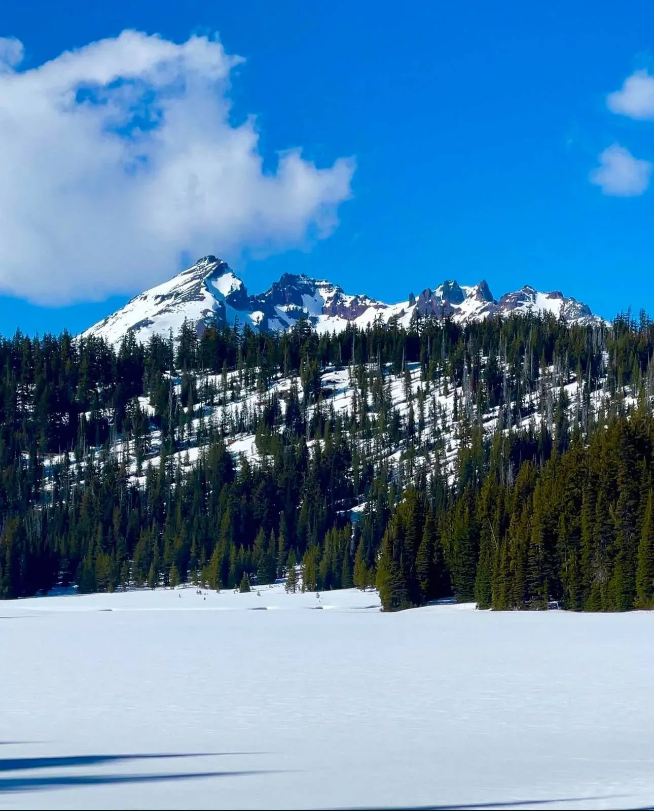 The jagged crater of Broken Top above a frozen lake.